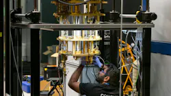 Engineer operating advanced quantum computing equipment through glass in research lab with cryogenic cooling and braided tubing. Engineer operating advanced quantum computing equipment through glass in research lab with cryogenic cooling and braided tubing.