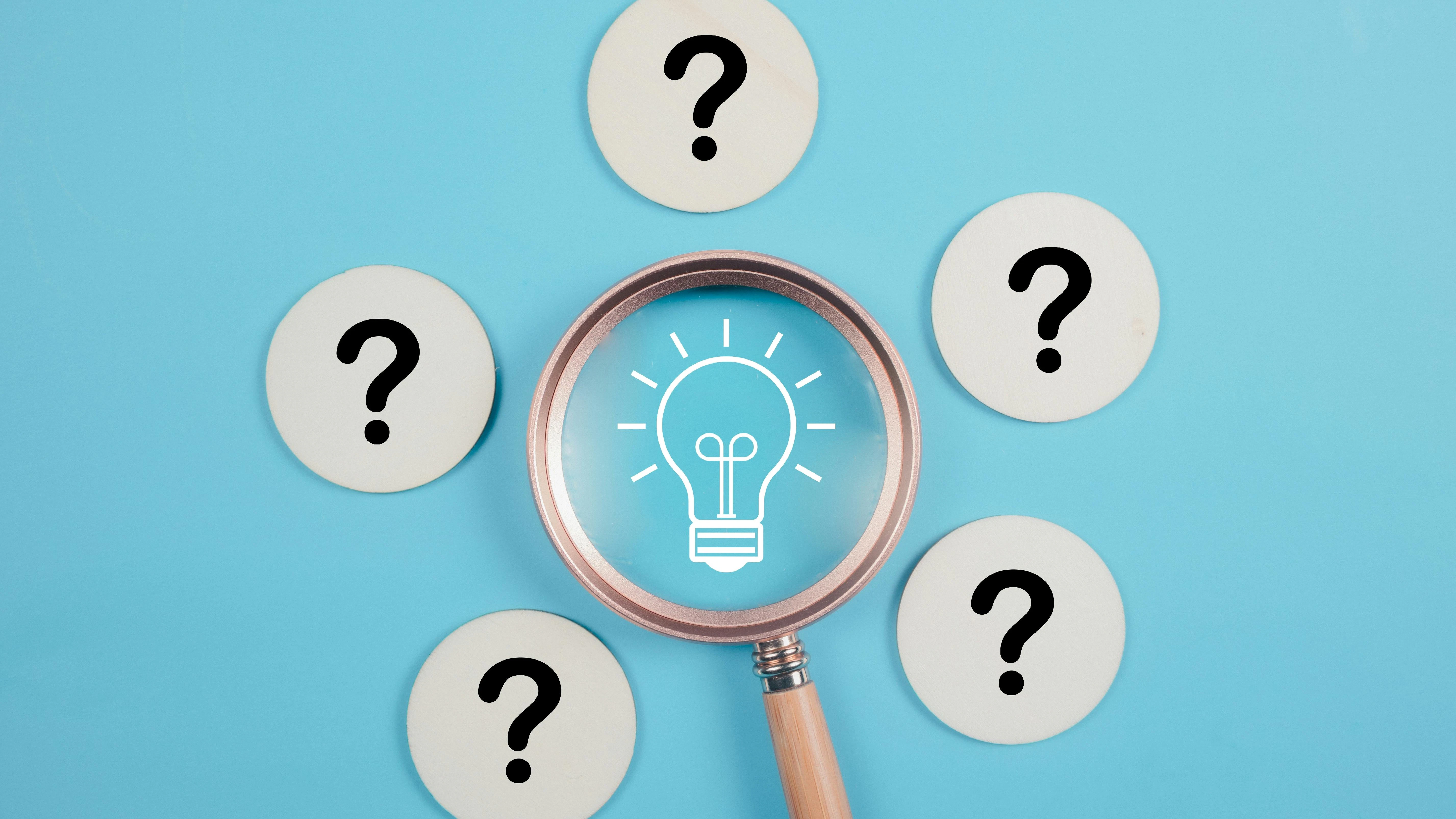 magnifying glass over image of light bulb surrounded by five question marks