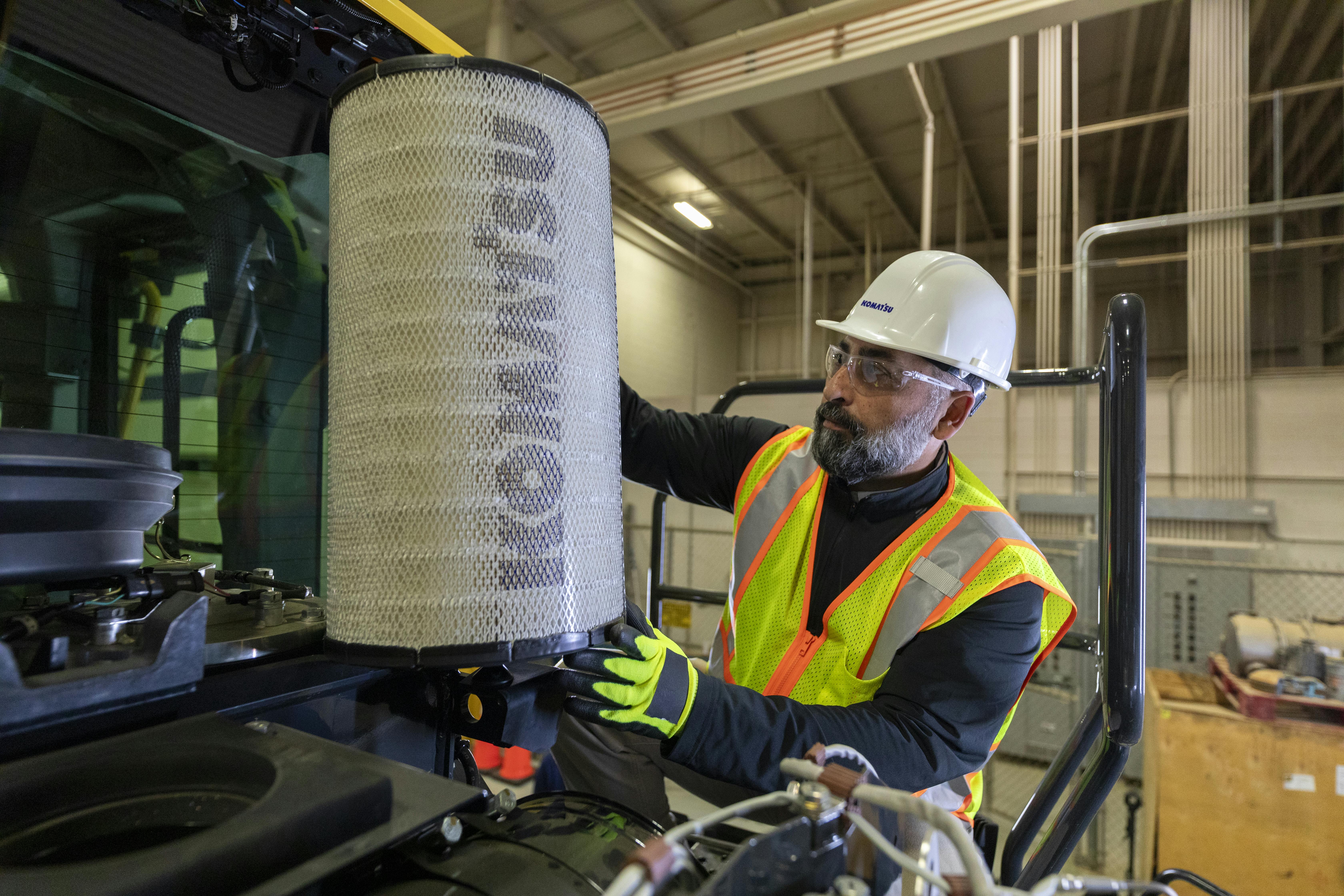 Komatsu wheel loader with a mechanic taking out the filter