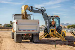 John Deere backhoe loader loading a truck. John Deere backhoe loader loading a truck.