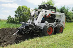 Bobcat 630 skid steer with a trencher attachment in the ground Bobcat 630 skid steer with a trencher attachment in the ground
