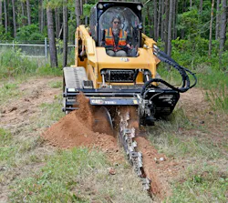 Caterpillar t315 trencher attachment slicing through soil Caterpillar t315 trencher attachment slicing through soil