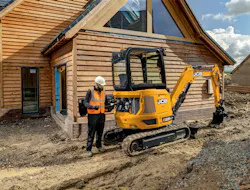 JCB's 25Z mini excavator. Man checks the engine oil by a house. JCB's 25Z mini excavator. Man checks the engine oil by a house.