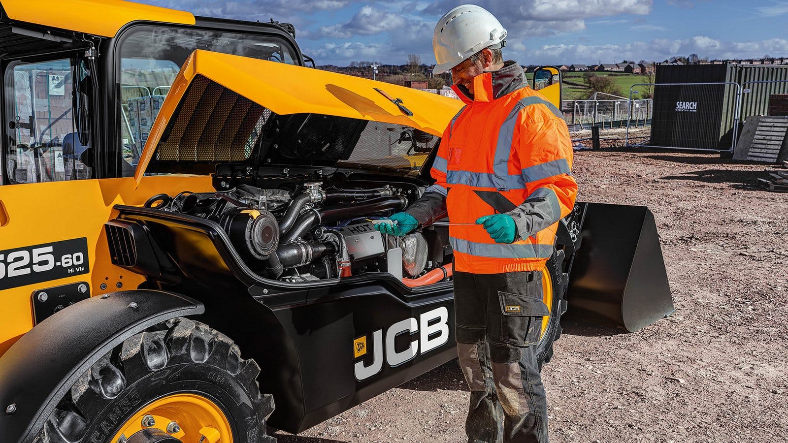 An operator checks the oil on a JCB telehandler.