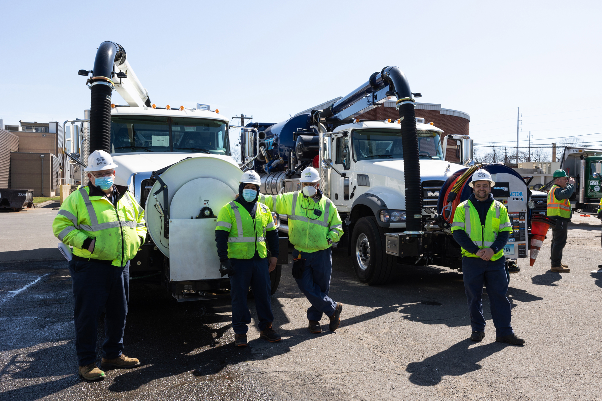 Cleaning crews in front of vacuum trucks.
