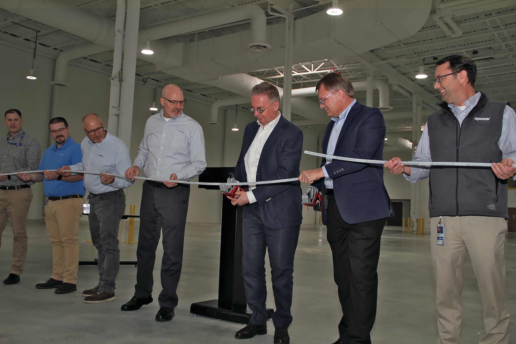 Michael Rauterkus, president and CEO, Uponor Group, (center) joins business leaders as he cuts the ceremonial PEX-a pipe to mark the opening of the company&rsquo;s $5.5 million, 25,000 sq. ft. expansion in Hutchinson, Minn.