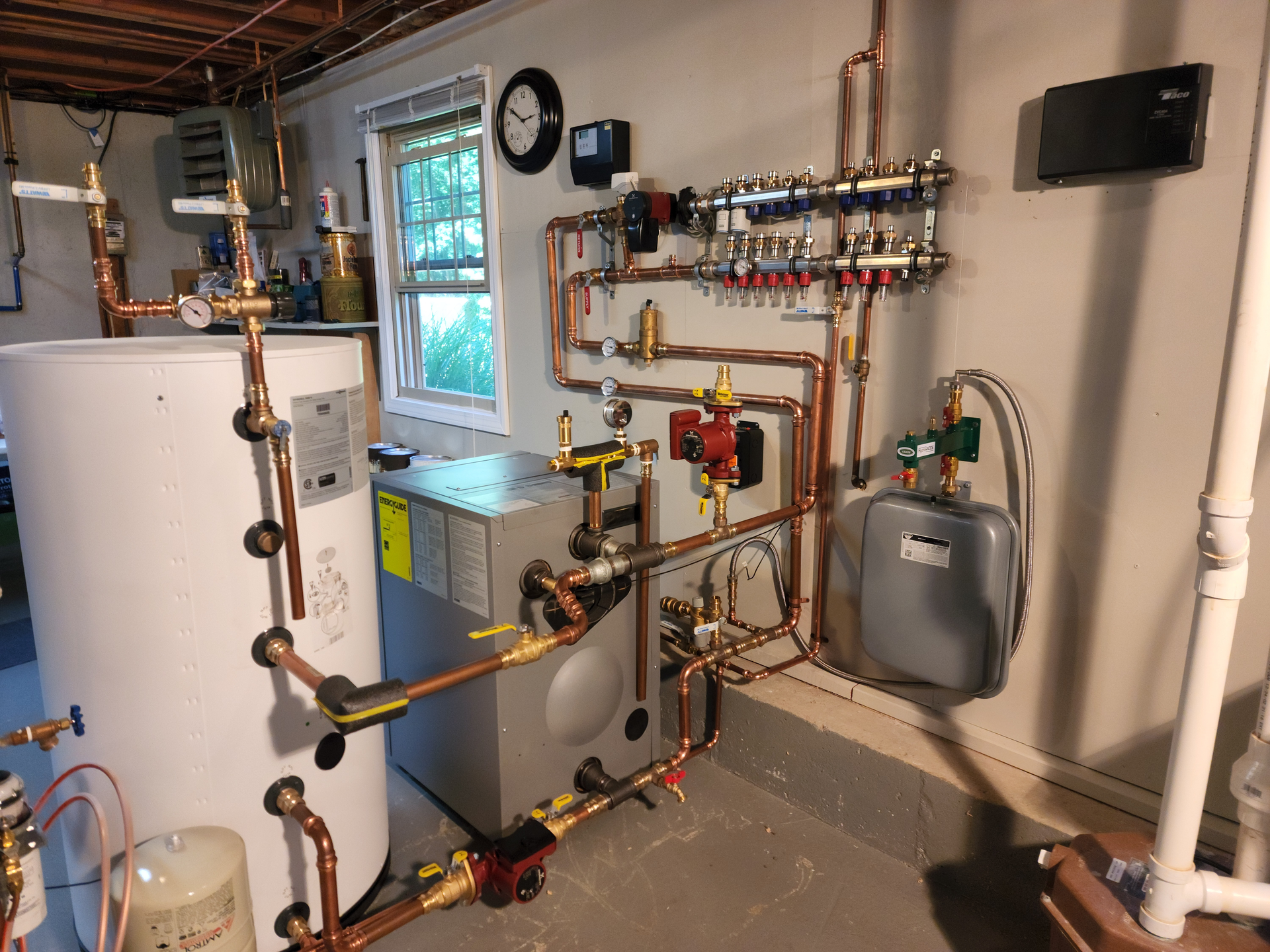 The new mechanical room. Left to right are a 42-gal. Viessmann Vito DHW tank, a Viessmann Vito Rond cast iron boiler, a Grundfos circulator and (on the wall) a Zilmet Model ZFT expansion tank. Above, on the wall, is a Viega Model 12152 Enhanced Mixing Station (with another Grundfos circulator on the left-hand side).