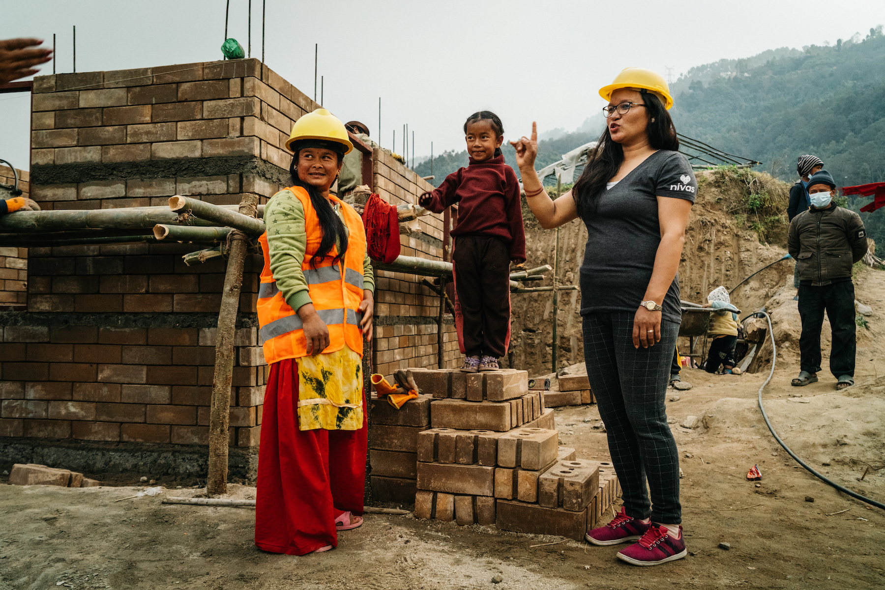 New homeowner Sabita T. taking a break on her job site with NIVAS Program Coordinator in Nuwakot, Nepal.