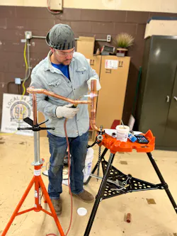 A tech soldering a copper joint. A tech soldering a copper joint.