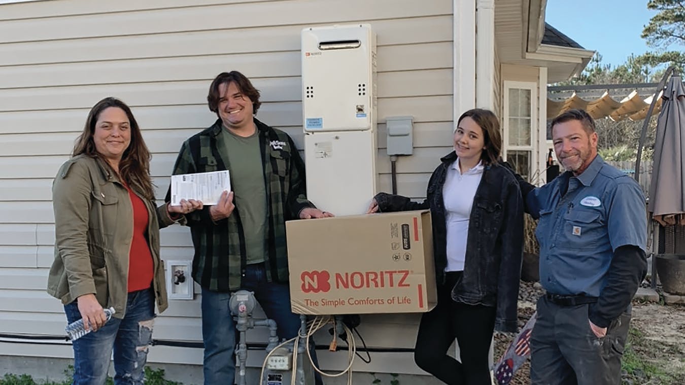 Kyndra Colosetti (far left) and Michael Stefans (far right) of Colosetti Plumbing partnered with Noritz America&rsquo;s tankless water heaters to donate an NR66 series to former veteran Brad Benjamin (center left).