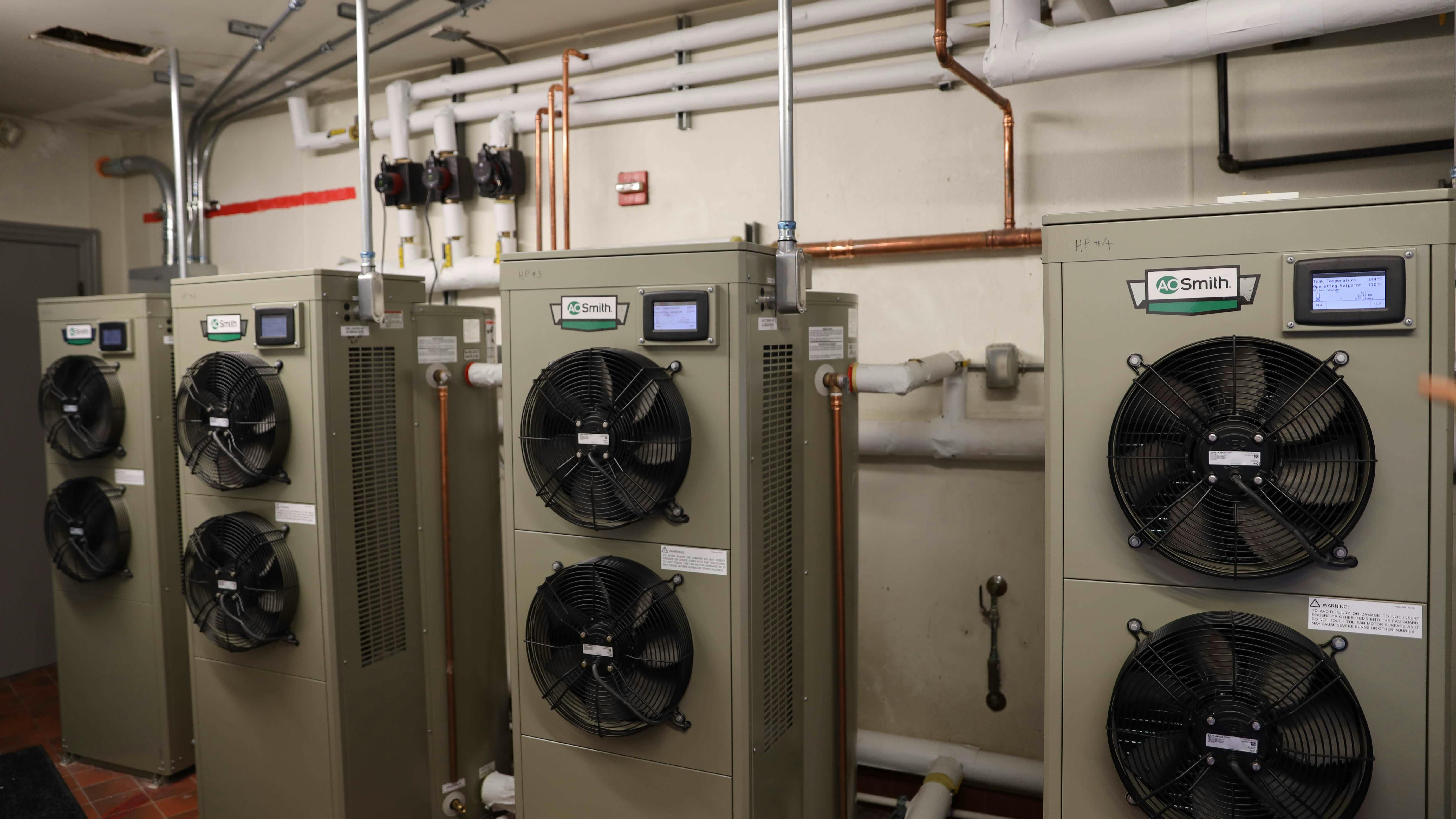 The four CHP-120 Fully Integrated Commercial Heat Pump Water Heaters (HPWH) in the mechanical room, along with piping and circulators.