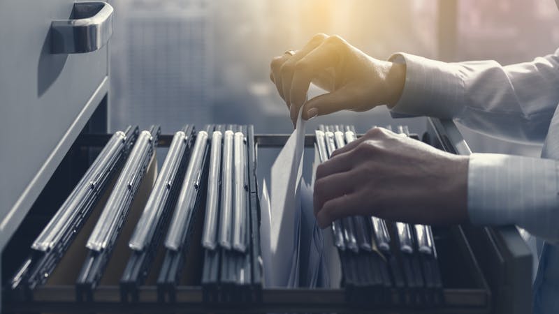 Office clerk searching files in the filing cabinet.