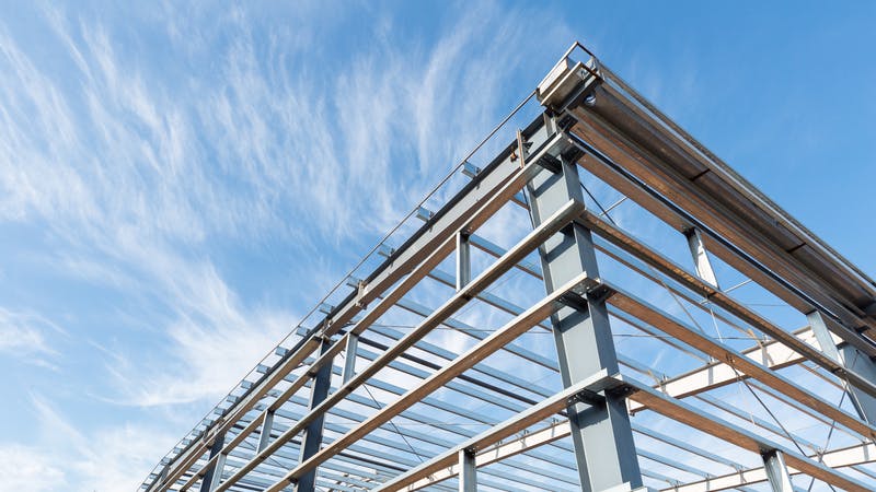 Steel frame workshop is under construction against a blue sky