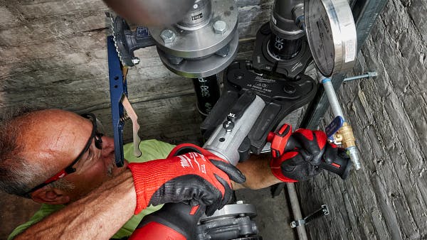 Plumber using a press tool.