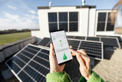 Woman monitors energy production from the solar power plant with mobile phone Woman monitors energy production from the solar power plant with mobile phone