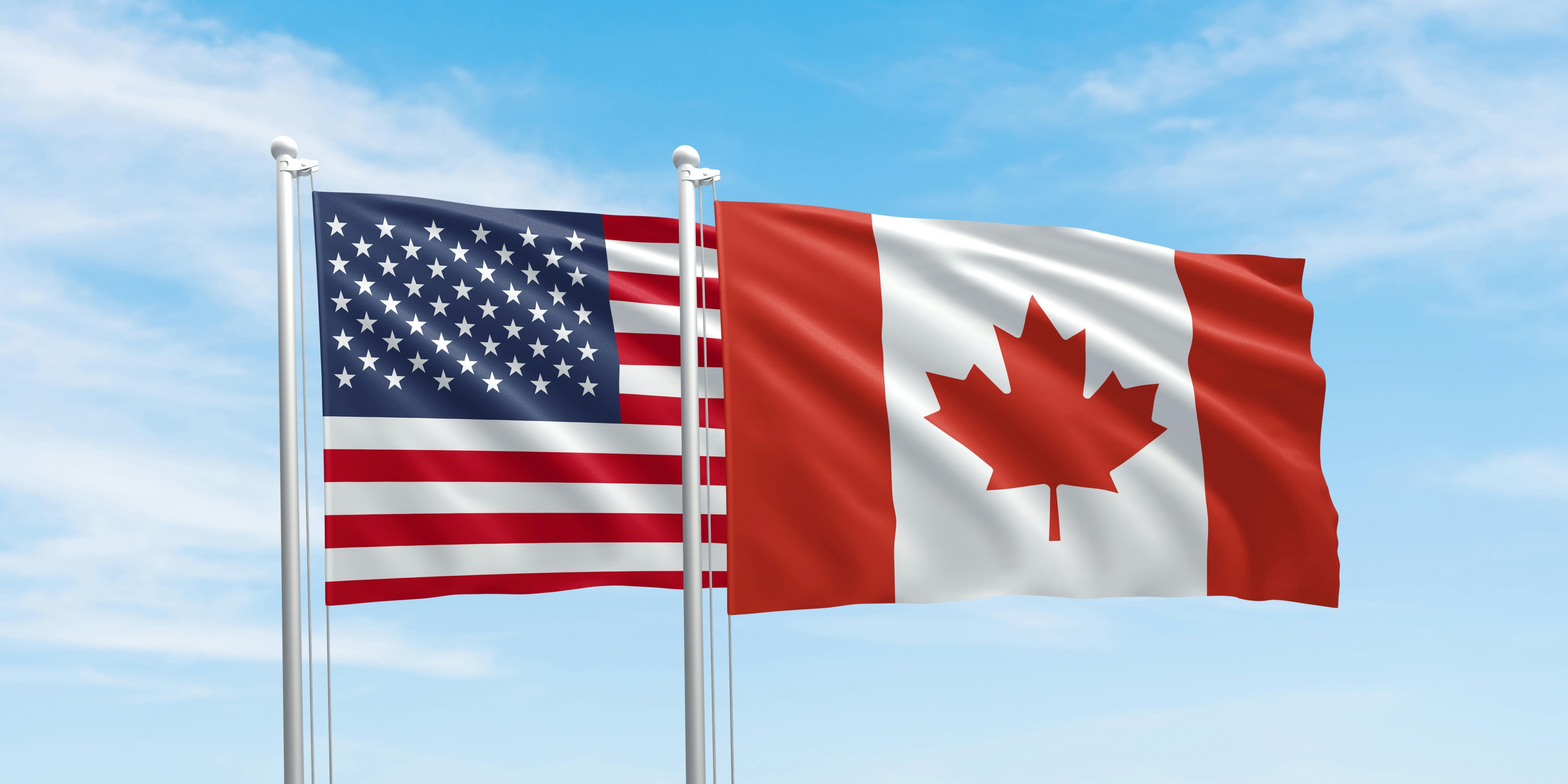 United States and Canada flags, two flags waving on sky background