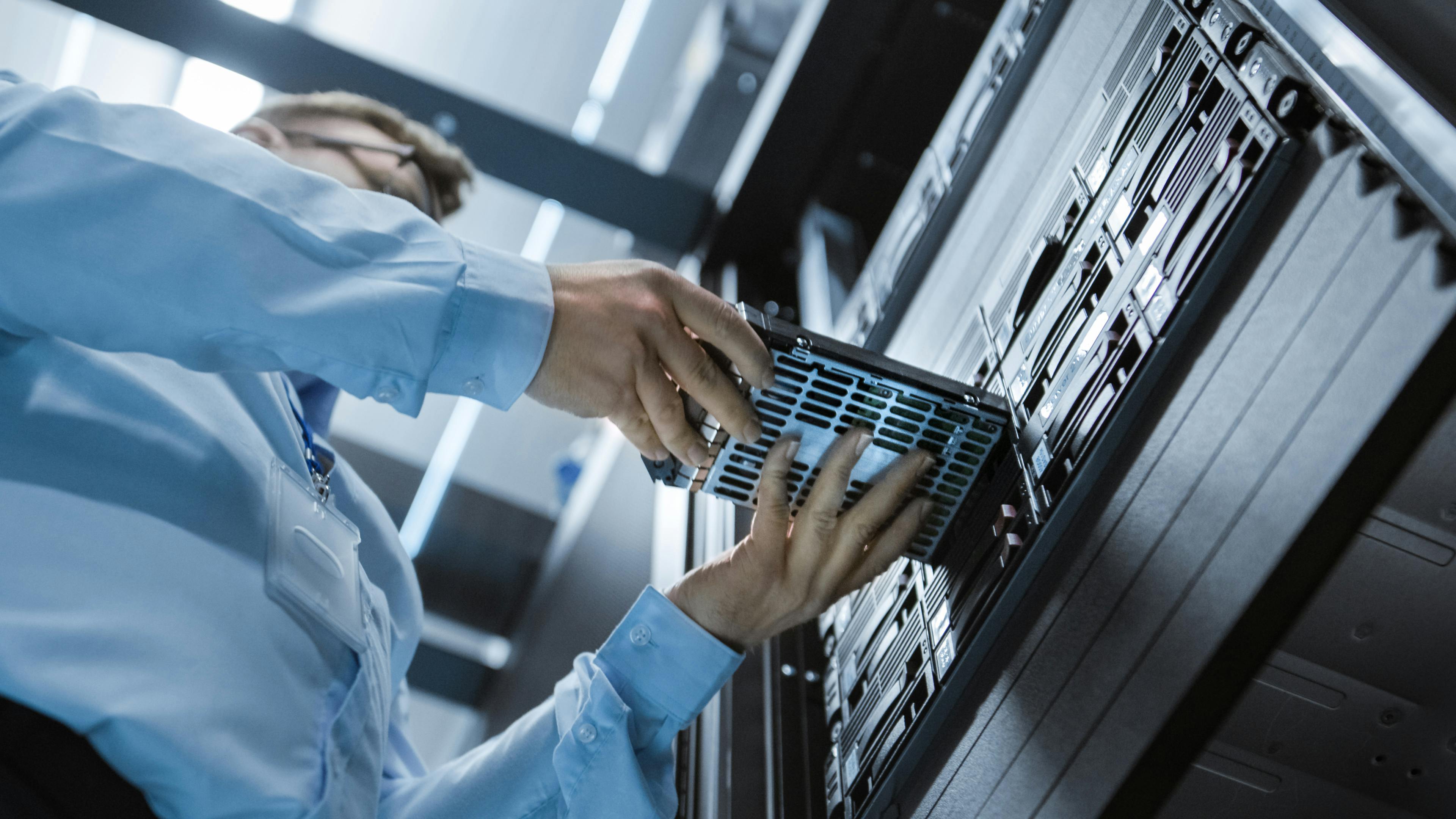 Low Angle Shot In Fully Working Data Center IT Engineer Installs Hard Drive into Server Rack