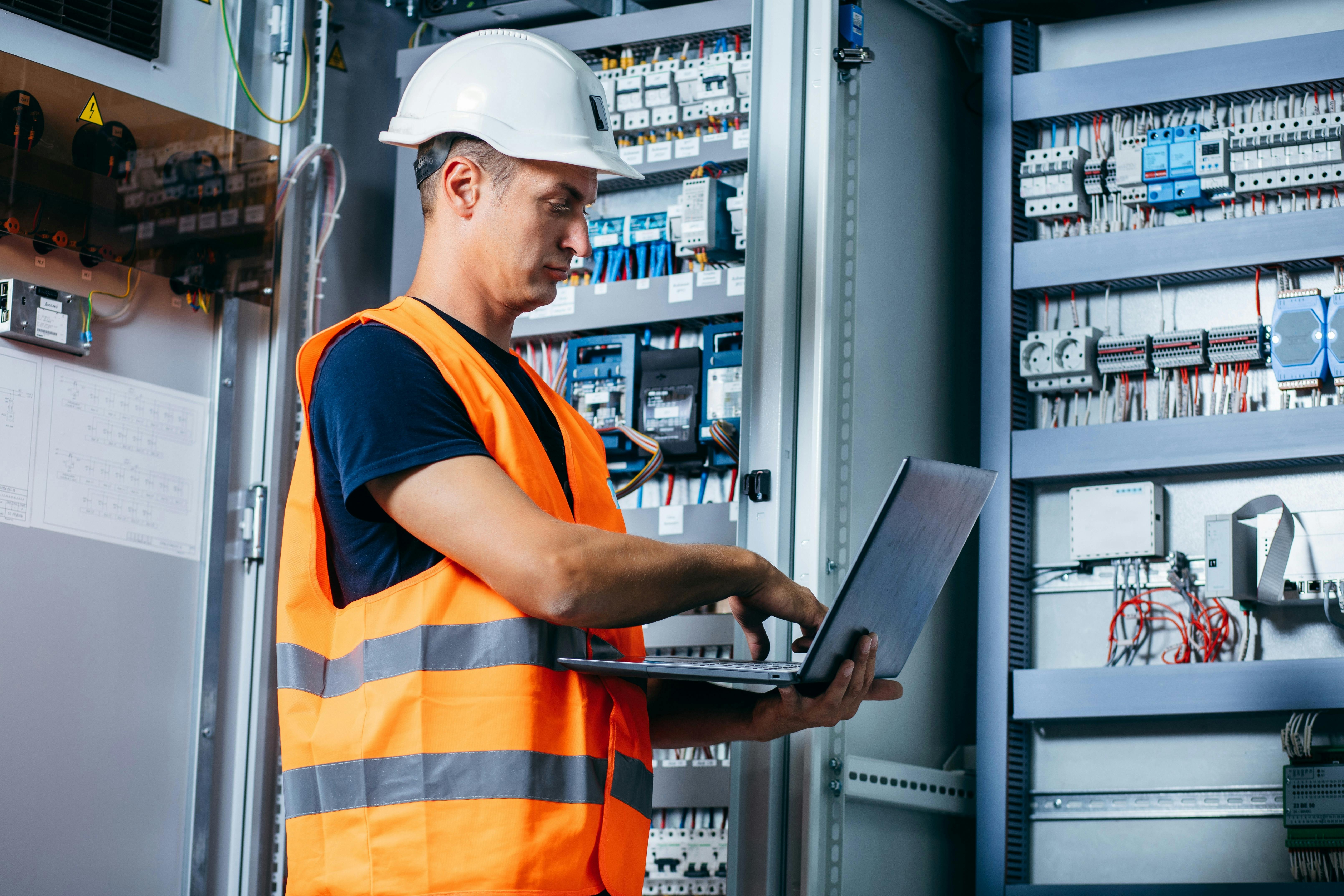 Adult electrician builder engineer testing and screwing equipment in fuse box and repairing of modern electricity power station