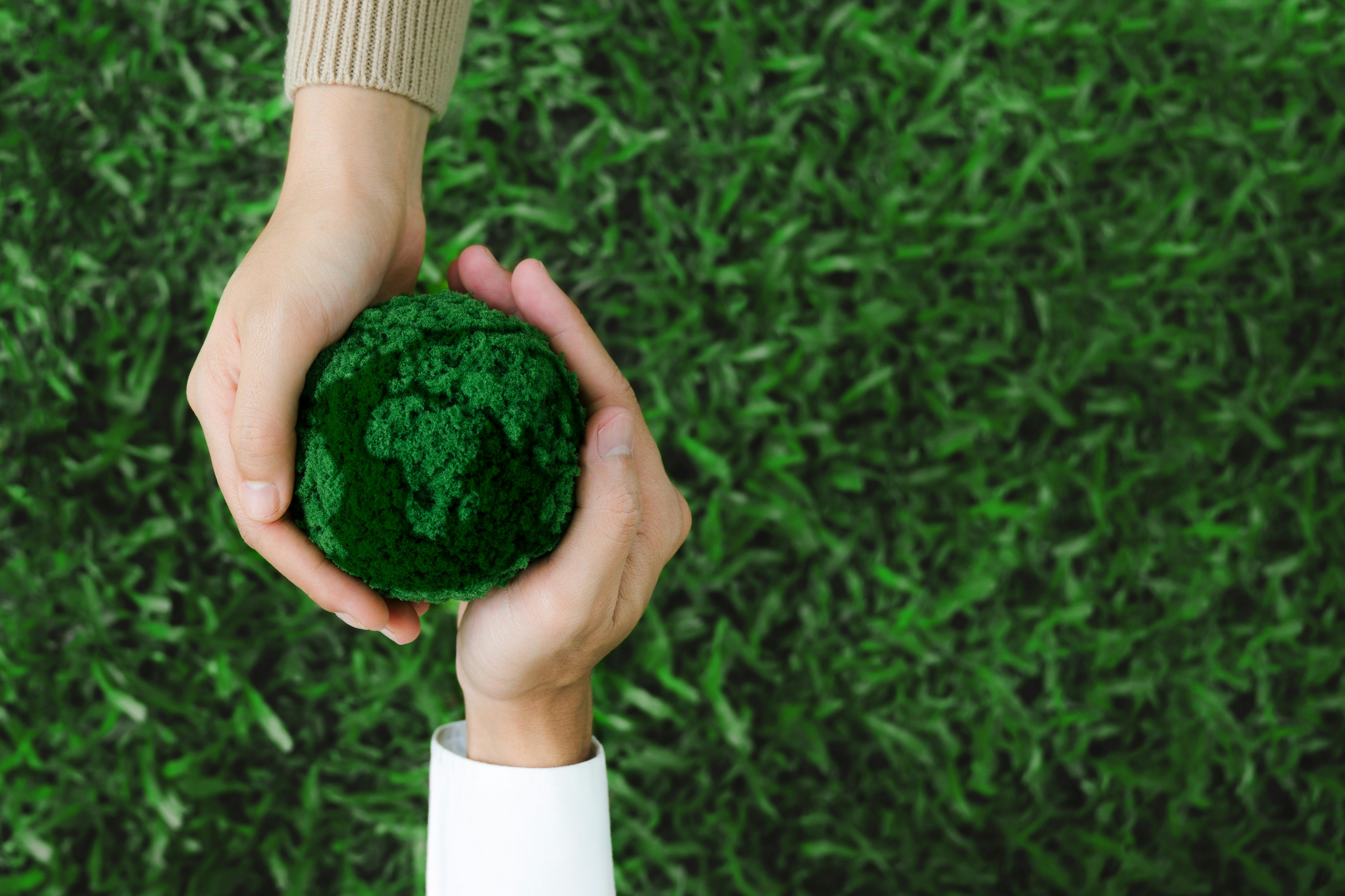 Two hands holding green earth together on nature background for the Sustainable Development Goals