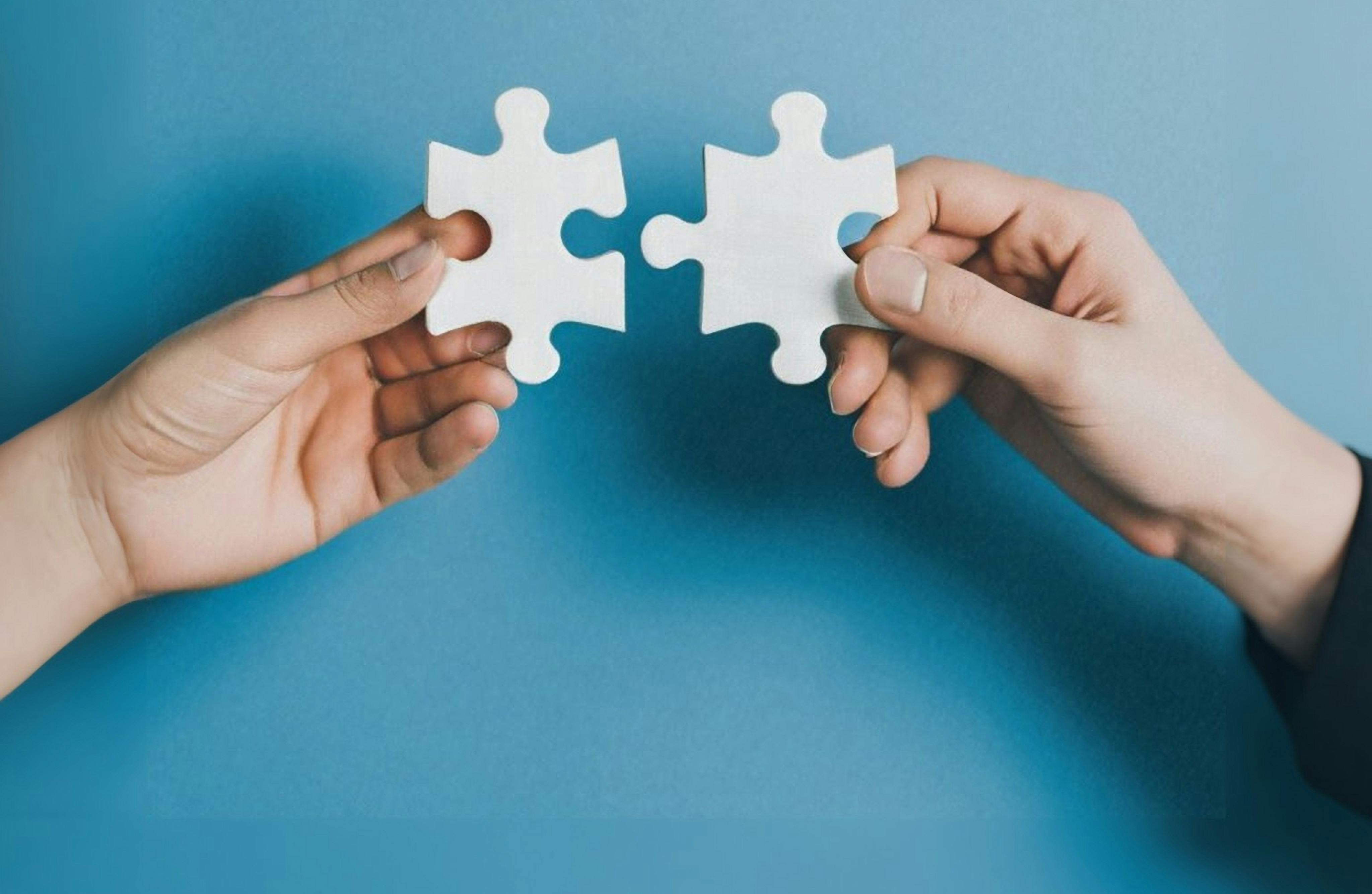 Hands bringing puzzle pieces together