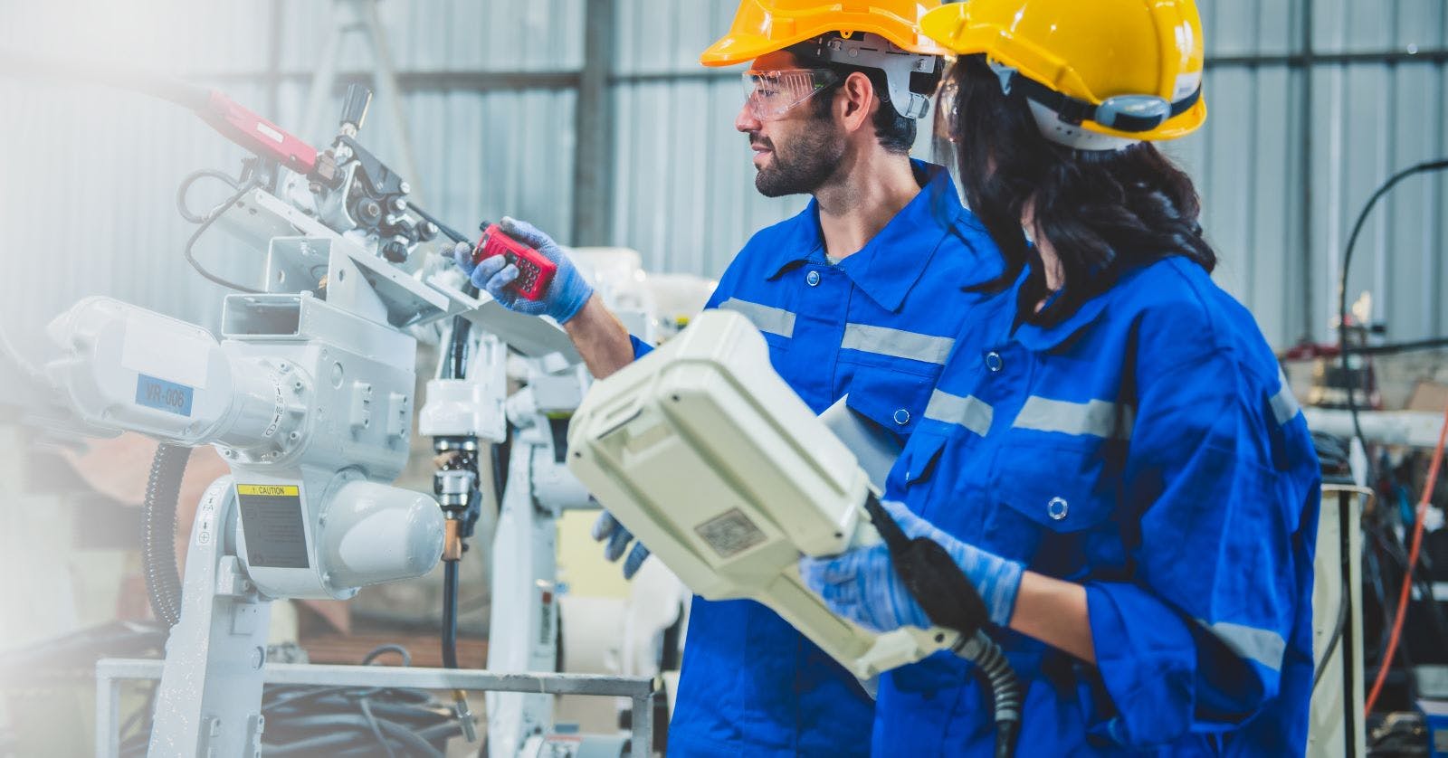 Engineers team mechanic using computer controller Robotic arm for welding steel in steel factory workshop. Industry robot programming software for automated manufacturing technology