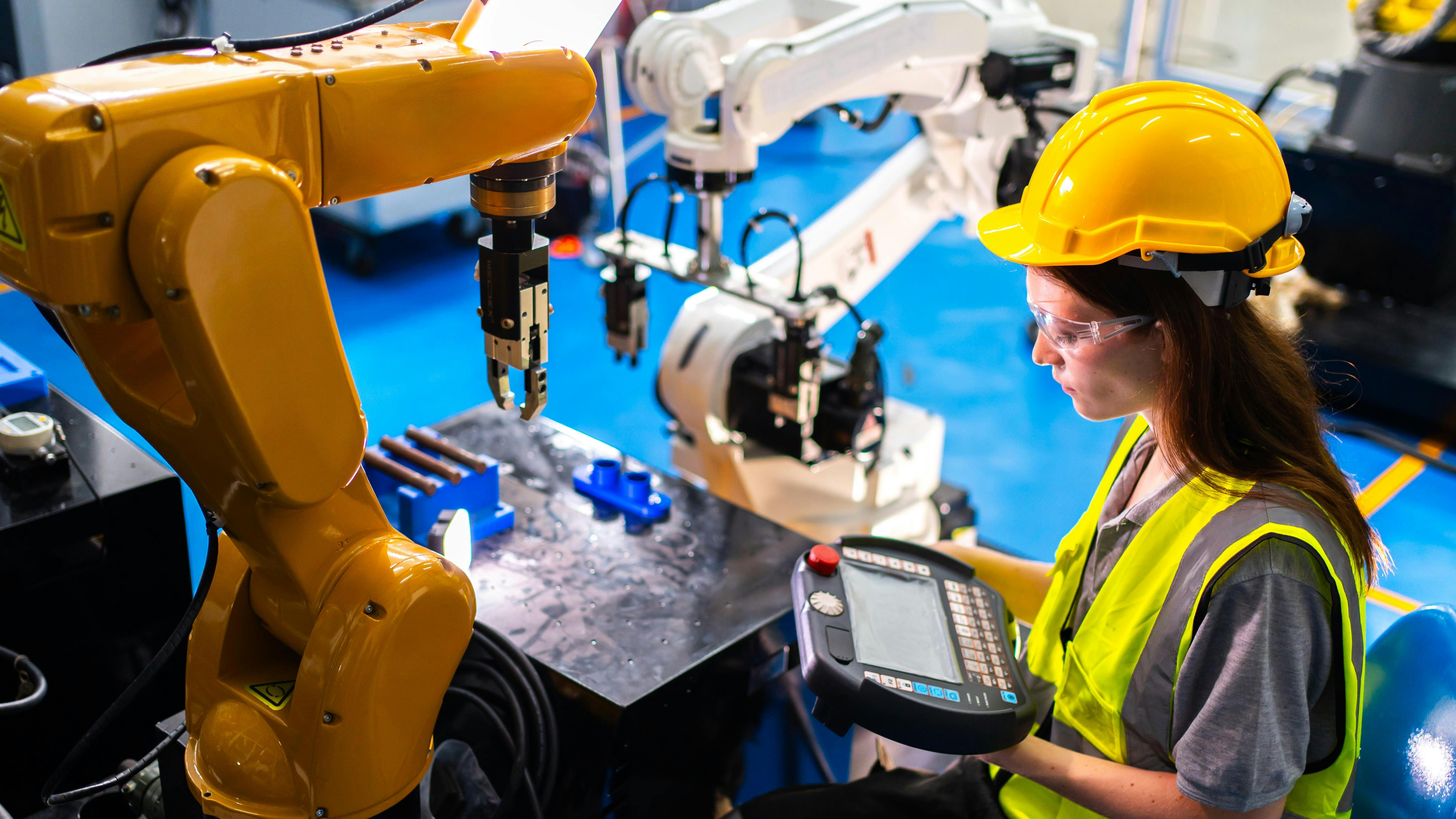 Professional and intelligence female engineer used her technical hard skill to fix, repair or maintenance machine robotic arm in factory or industrial, examining or welding automobile machine workshop