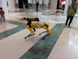 A yellow multipurpose robot dog or robodog by Boston Dynamics being exhibit at a shopping center A yellow multipurpose robot dog or robodog by Boston Dynamics being exhibit at a shopping center