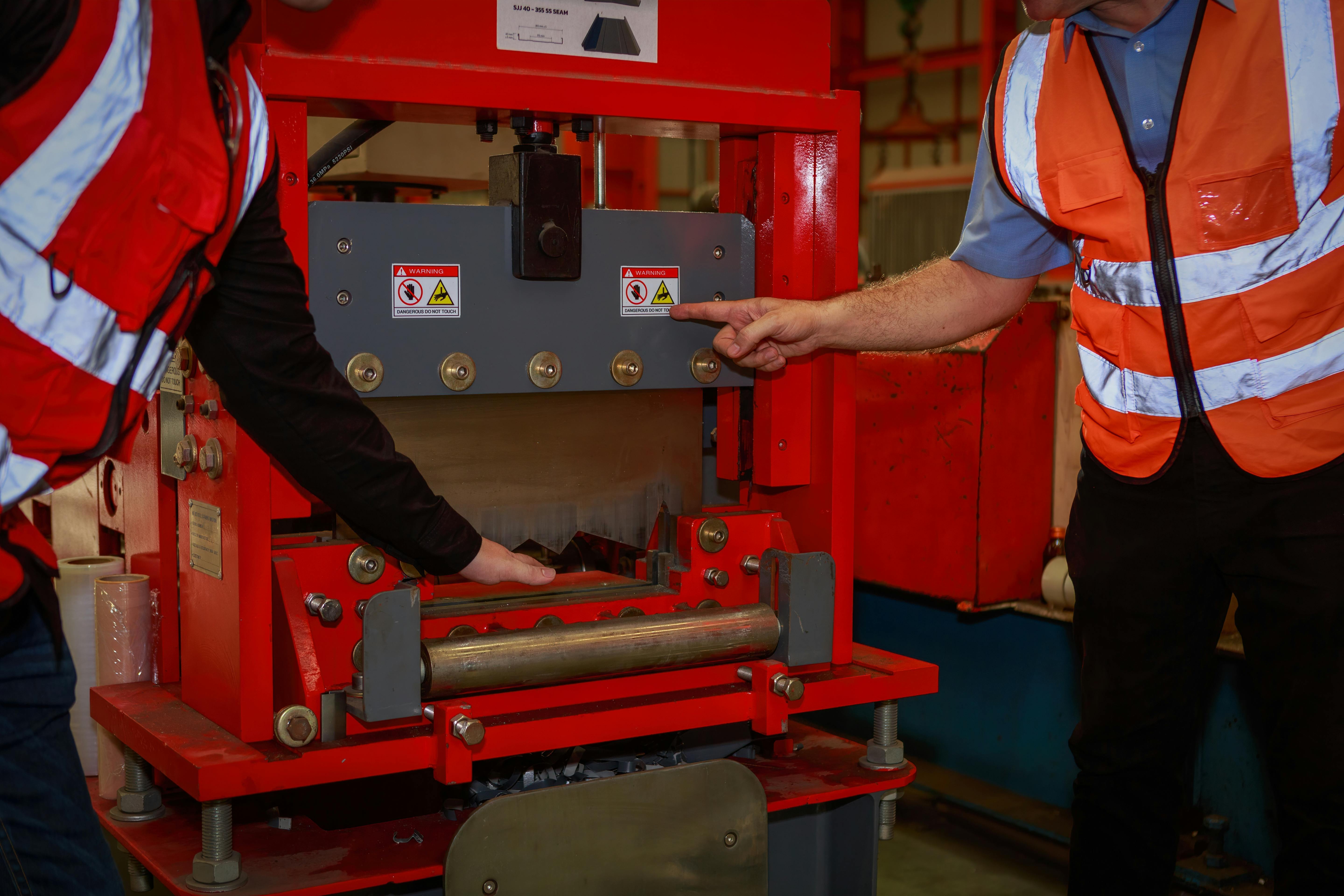 The manager is explaining the precautions and safety warning signs. attached to the machine for the engineering team in sheet steel factory Safety symbol concept in the work industry, engineering.