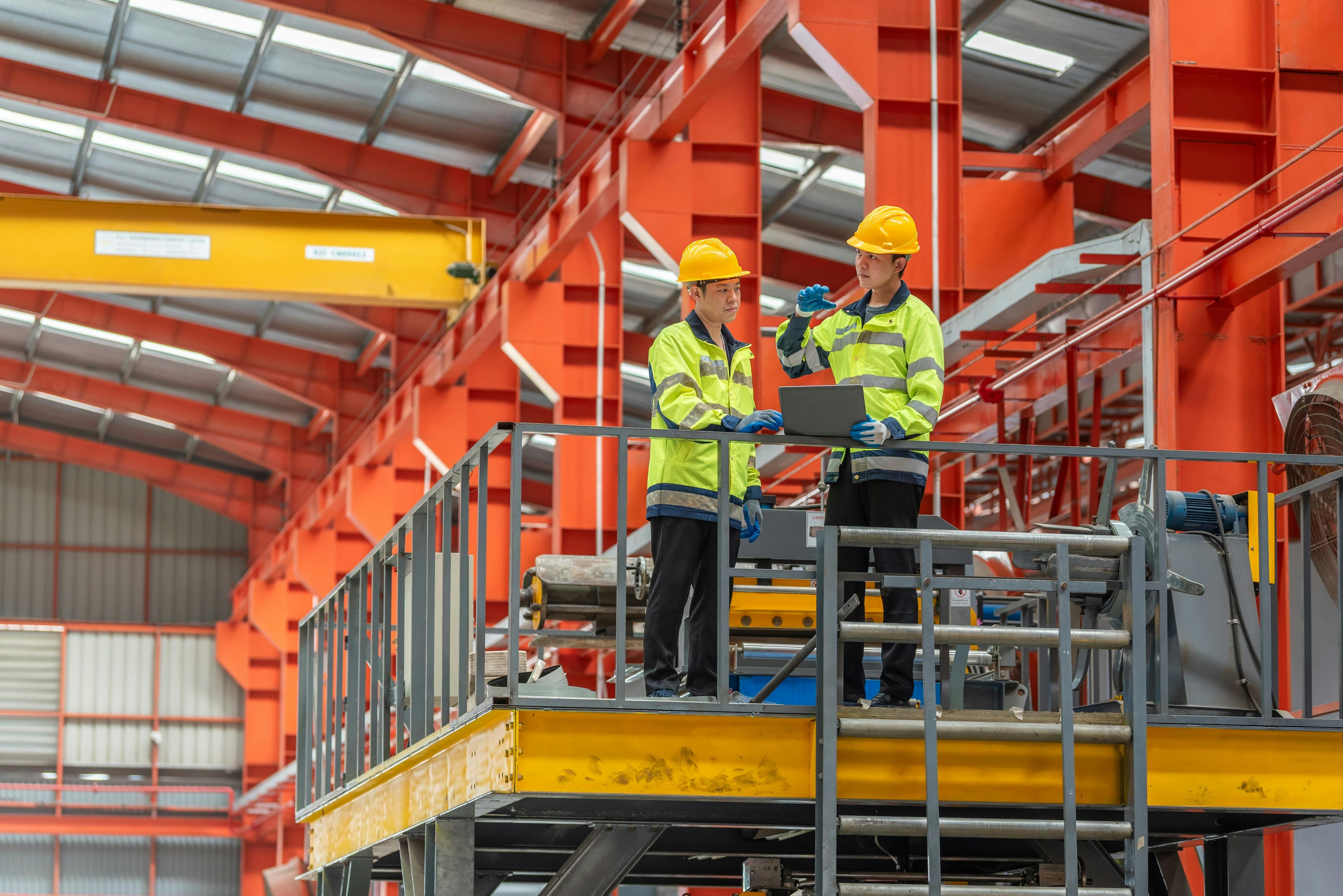 industrial apprenticeship. mentor teaching new employees trainee operating machine looking monitors and check machinery. Two industrial engineer technician In factory explain operating machine.
