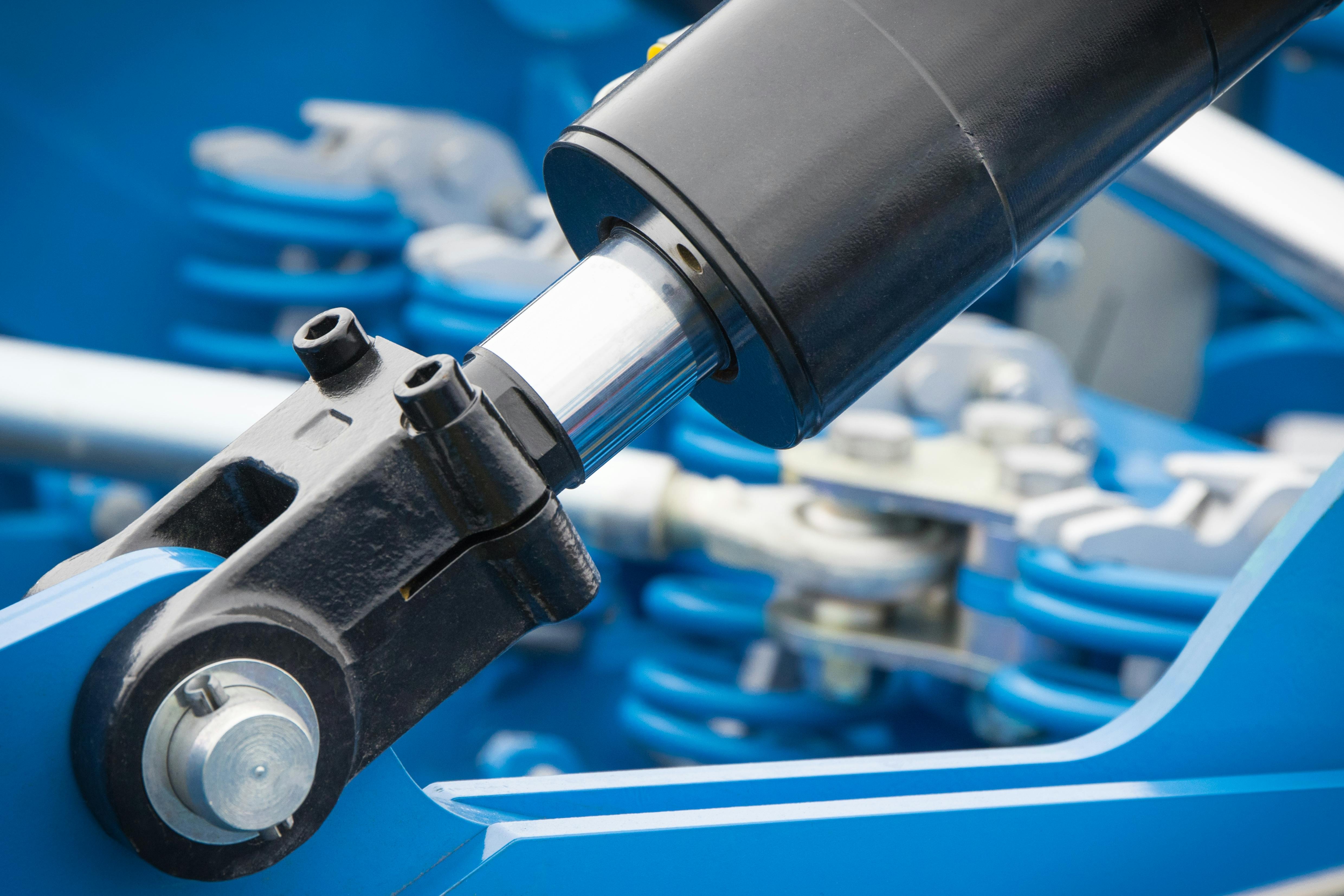 Black piston or actuator as part of blue pneumatic or hydraulic machine. Technology and engineering