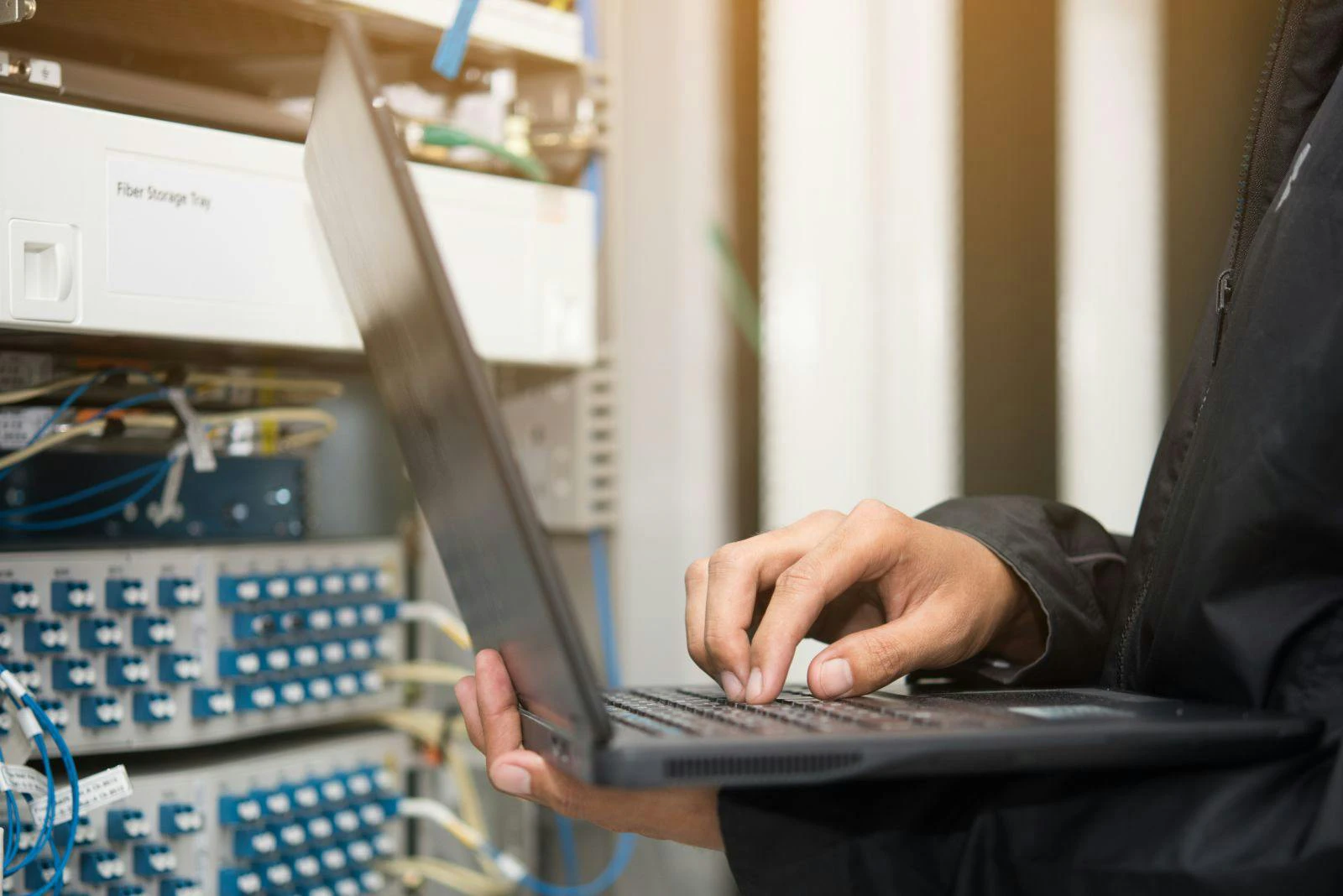 Technician using laptop in server room.