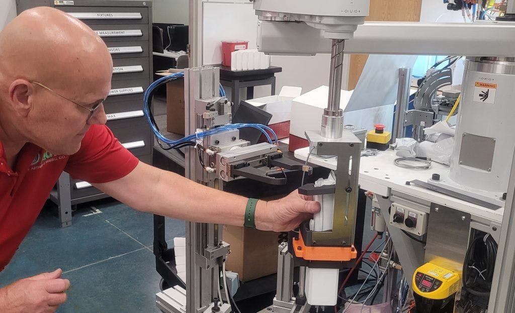 In system integrator Arthur G. Russell&rsquo;s R&D and mock-up area in Bristol, Conn., senior R&D engineer Jerry Buchas adjusts a robot-actuated loader that brings a client&rsquo;s product to the proper location in a case, so its end-of-arm tooling (EOT) with an attached actuator can push the product into place. AGR helps customers develop, test, and derisk their designs and requirements for new end-products and production systems. Its clients want to derisk because shorter product lifecycles and increasing demand for variety are compressing development and commissioning schedules.