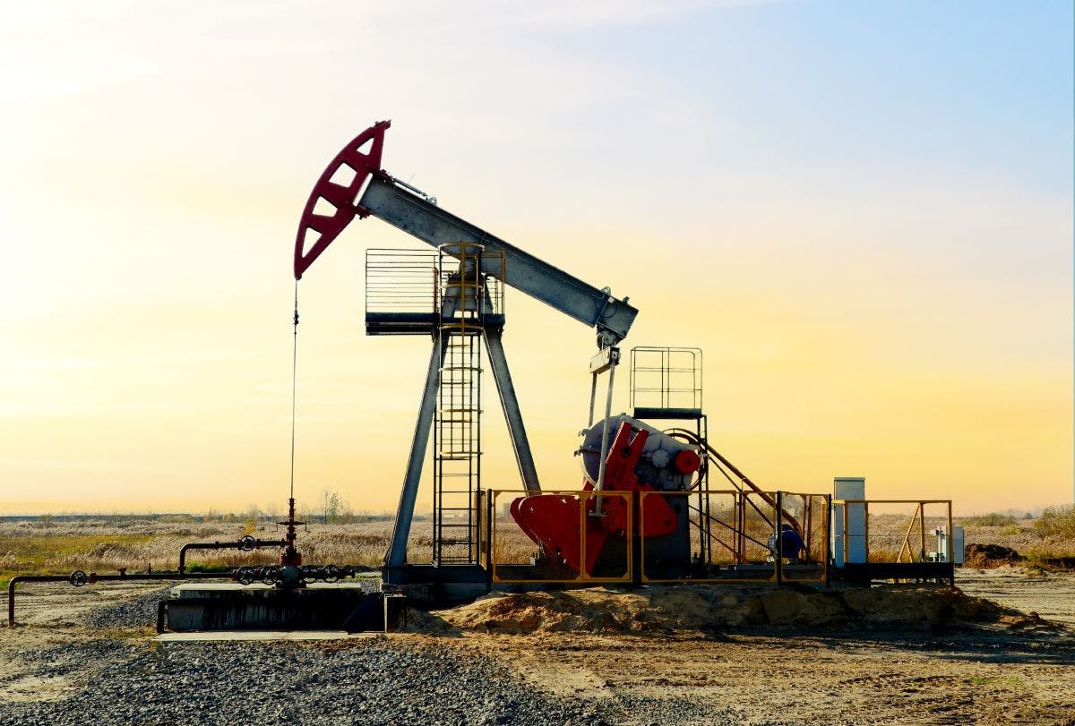 Crude oil pump jack at oilfield on sunset background