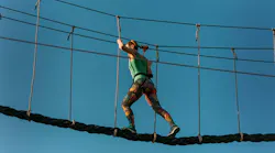 Skilled adult woman racing through the difficult course in the adventure park with ease Skilled adult woman racing through the difficult course in the adventure park with ease