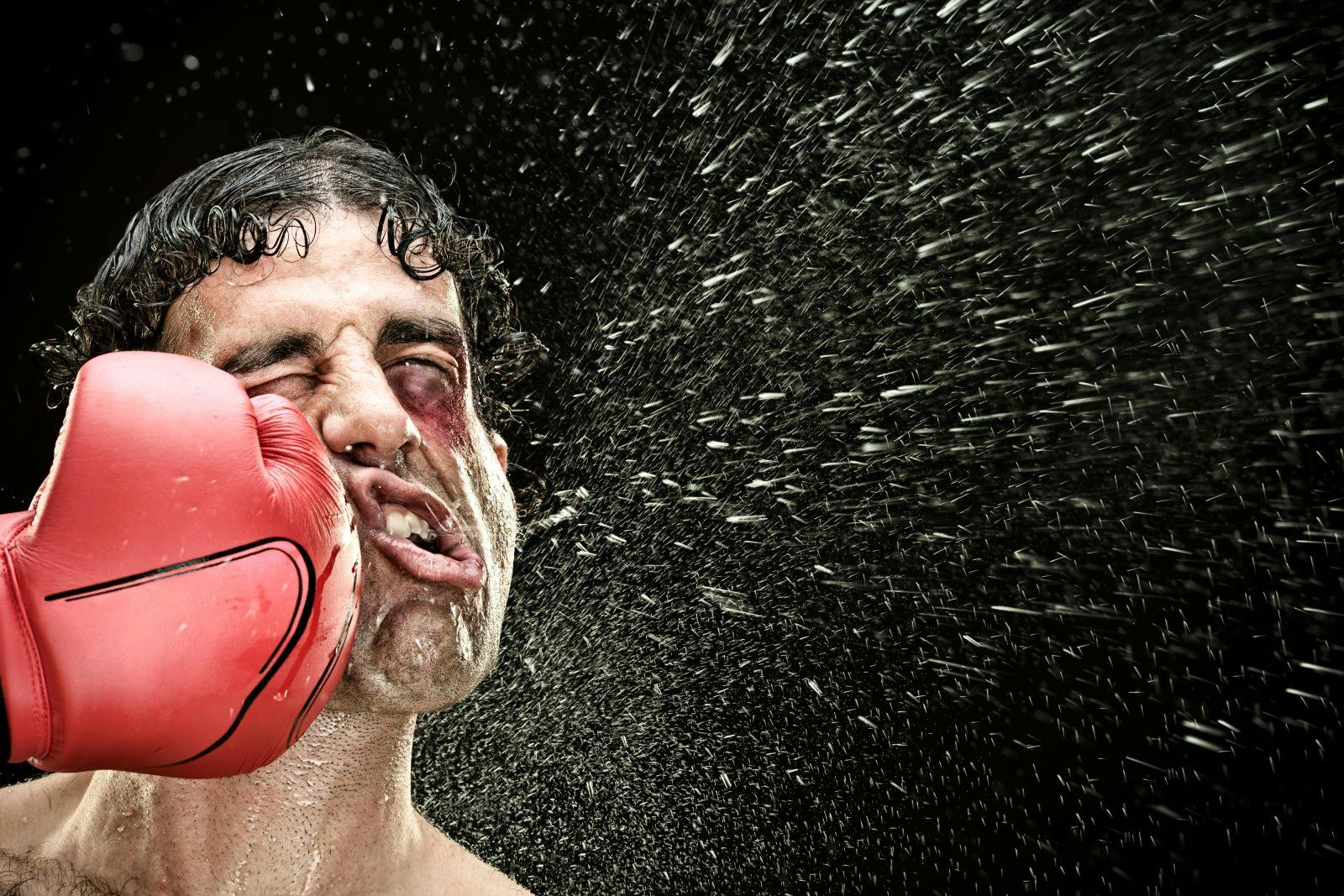 boxer man takes a punch in the face isolated on black.