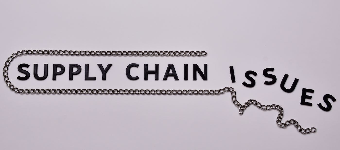 Supply Chain issues concept. Black letters with steel chain.