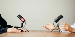 Two women in local broadcat studio recording audio podcast. Sitting opposite each other, hands close-up Two women in local broadcat studio recording audio podcast. Sitting opposite each other, hands close-up