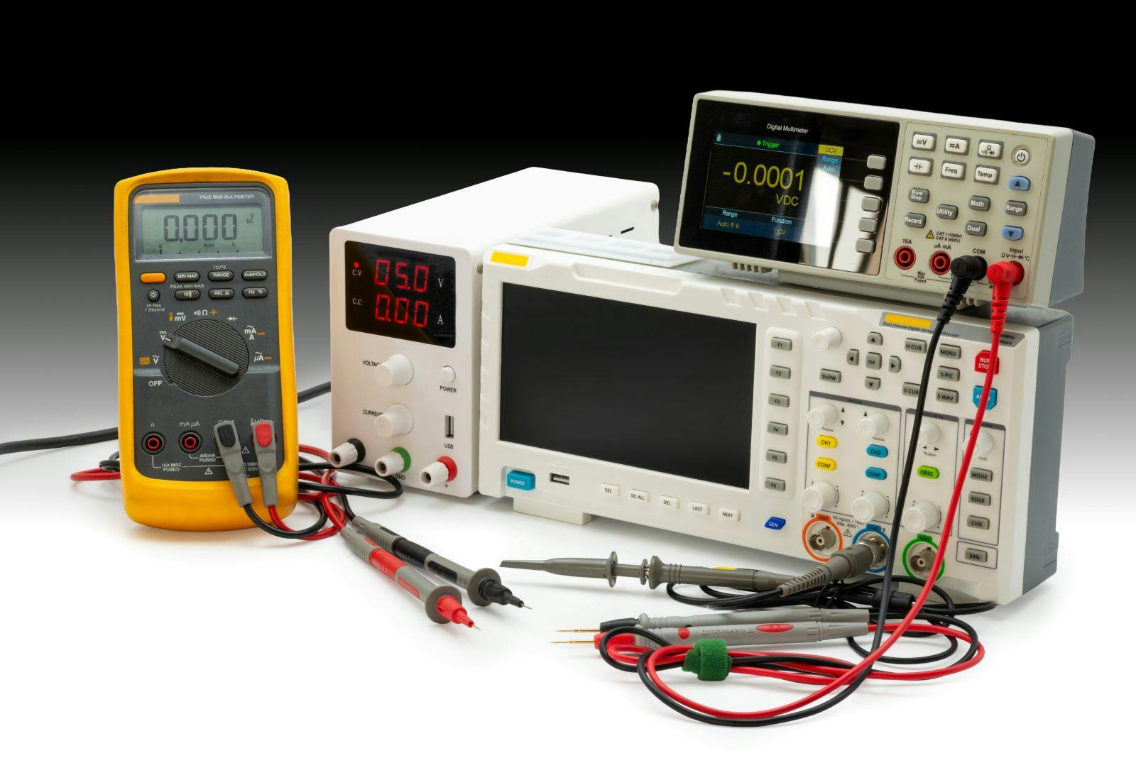 Various electronic testing devices are arranged on a workbench, showcasing multimeter readings and setup for analysis and measurement tasks.