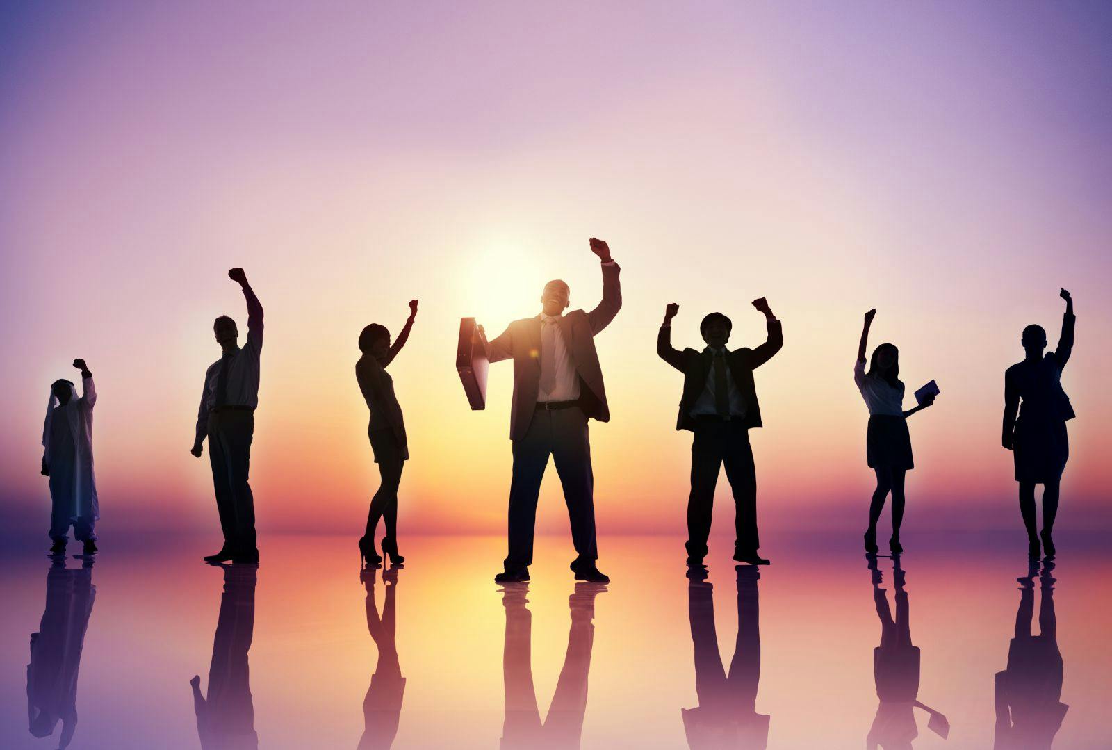 Silhouettes of accomplished businesspeople against a sunrise background.