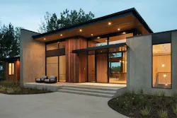 Exterior view of modern renovated home entrance with floor to ceiling windows and walnut door Exterior view of modern renovated home entrance with floor to ceiling windows and walnut door