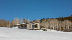 A contemporary home sits in a snowy hillside. A contemporary home sits in a snowy hillside.
