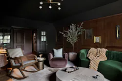 Moody living room with dark wood wall paneling and jewel-toned furniture Moody living room with dark wood wall paneling and jewel-toned furniture