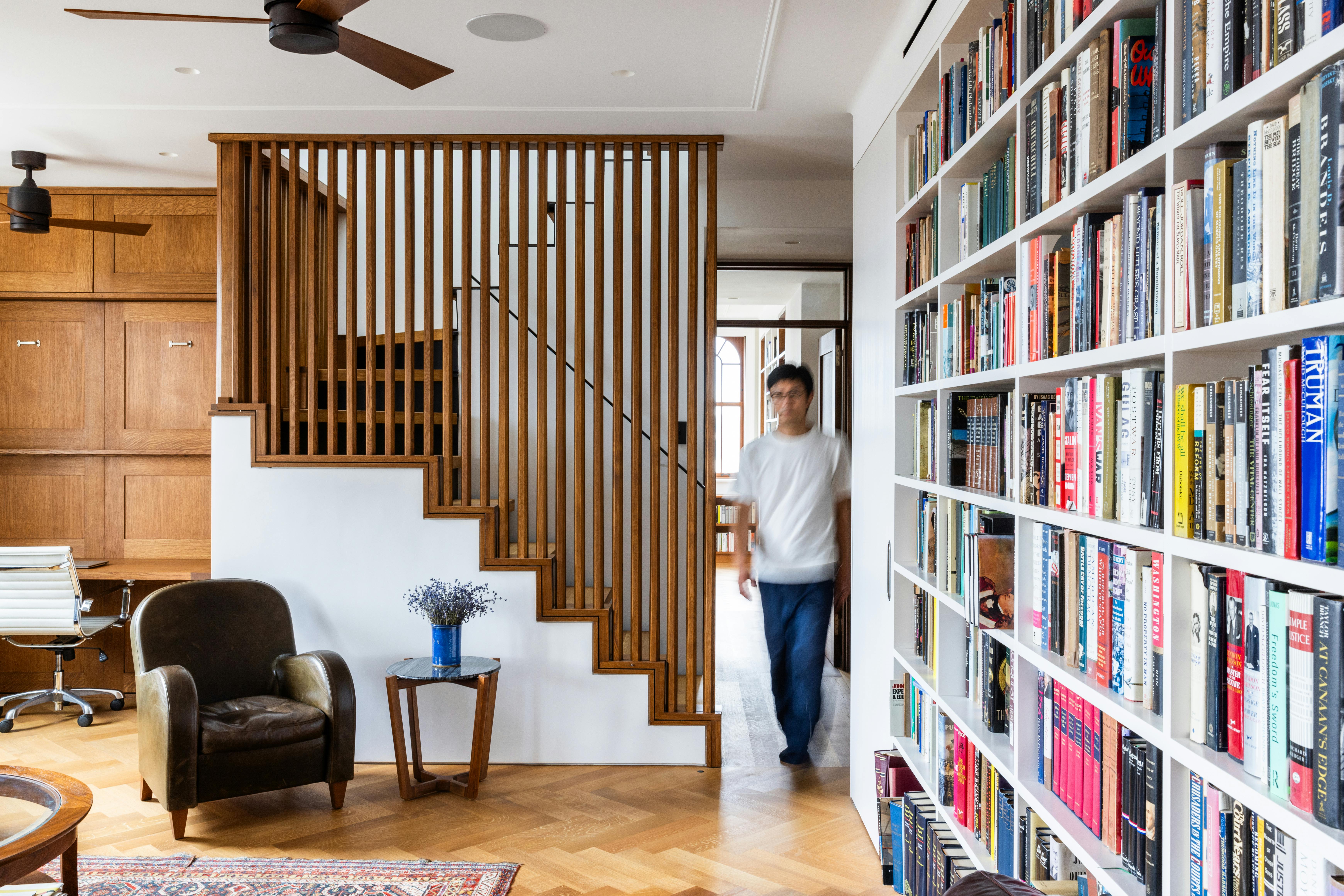 Blurrred image of someone walking into a living room, where a staircase featured sliding louvered doors to create privacy when needed