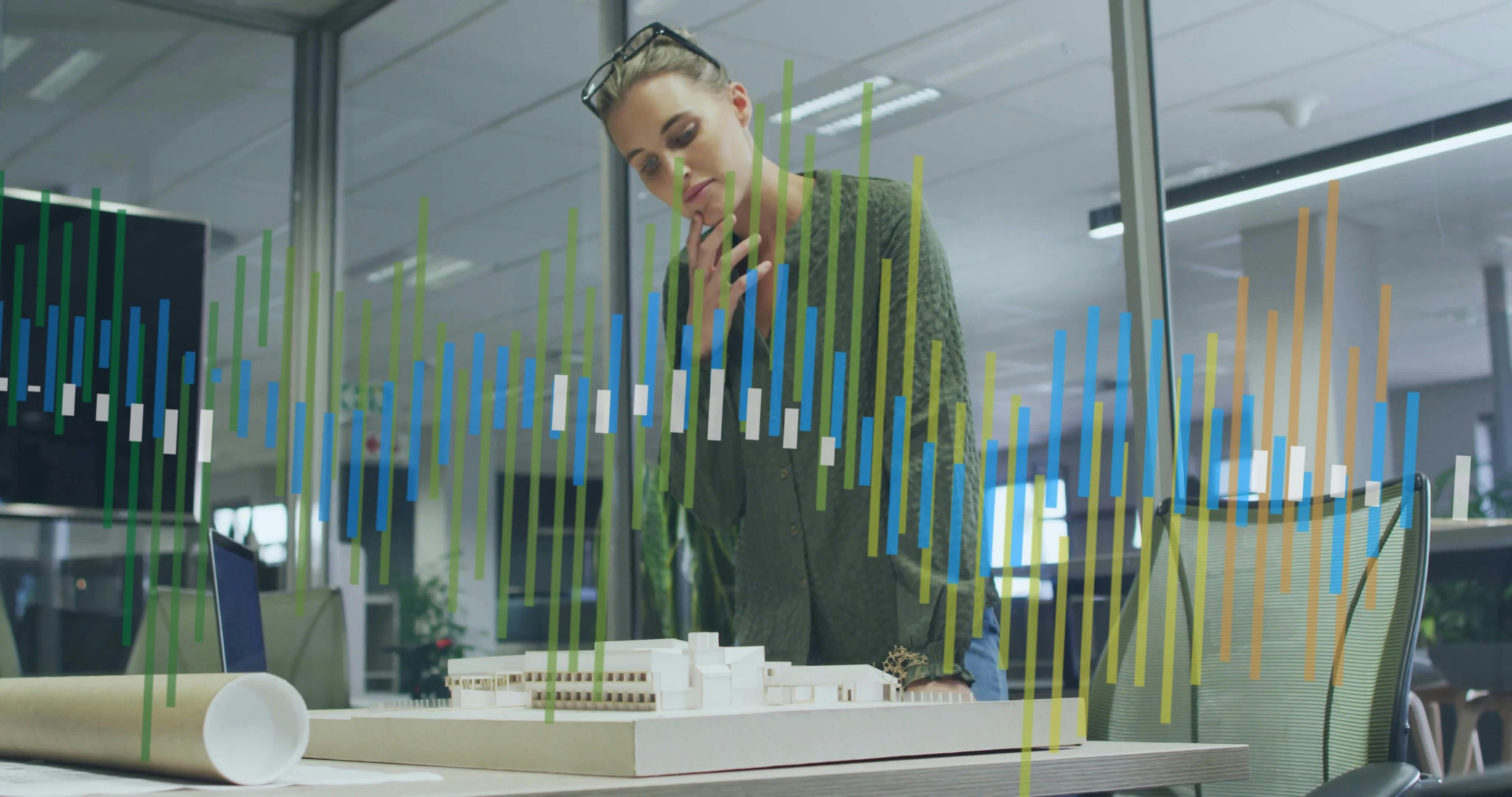 architect examining a model of a project with technology images all around