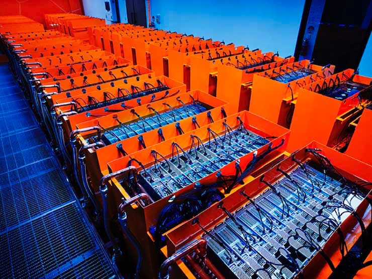 A look inside a DUG immersion-cooled data hall, showing the cooling enclosures filled with dieletric fluid and the piping where the cooling loop enters the enclosure. The Skybox deployment will use more than 700 of these tanks. (Photo: DownUnder GeoSolutions)