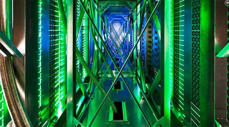 Inside the hot aisle of a Google data center, hundreds of fans funnel hot air from the server racks into a cooling unit to be recirculated. The green lights are the server status LEDs reflecting from the front of the servers. (Photo: Google)