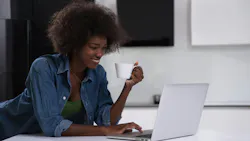 Woman enjoys a cup of coffee while using laptop Woman enjoys a cup of coffee while using laptop