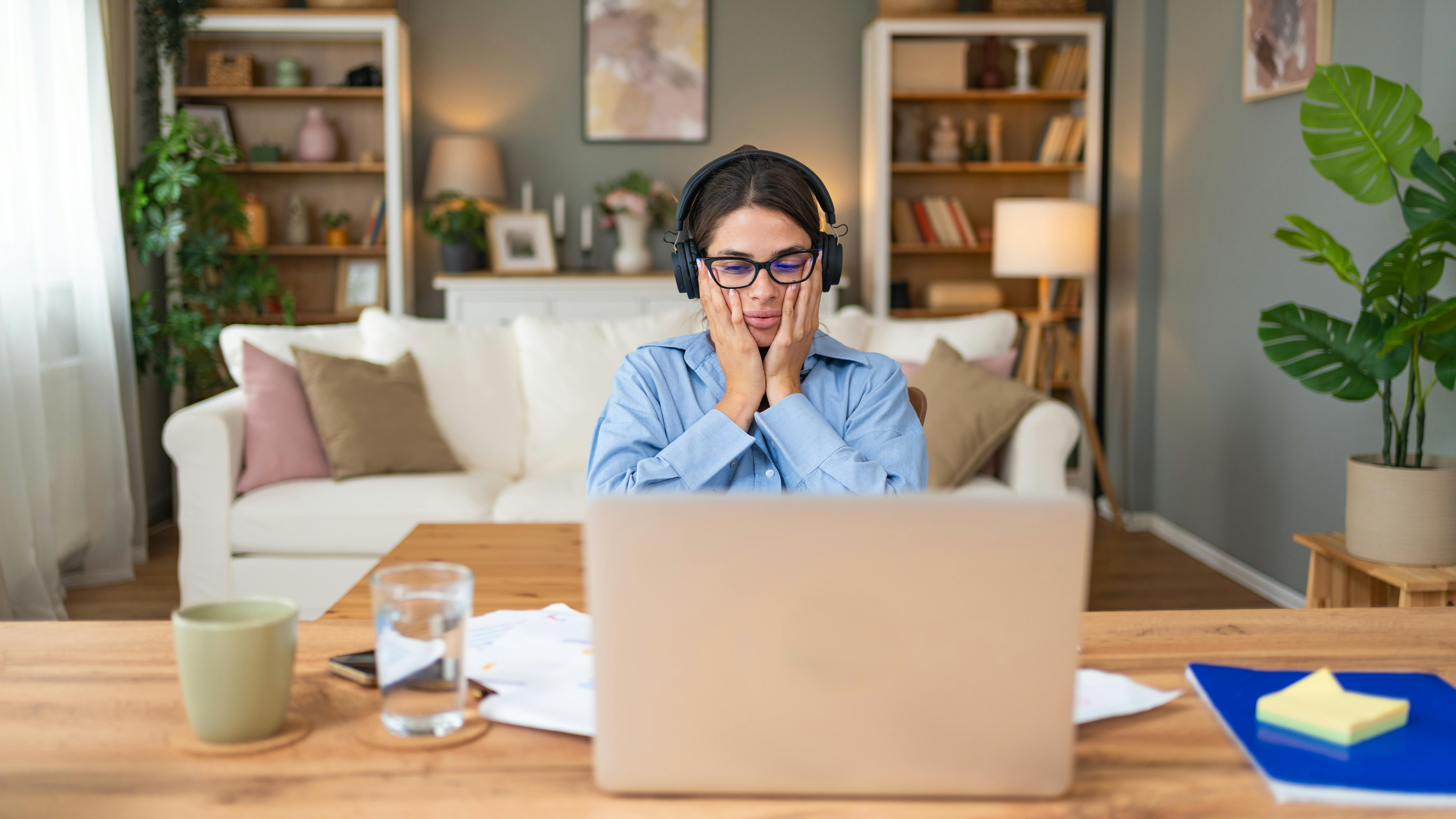 Woman sitting at laptop holding her face in her hands