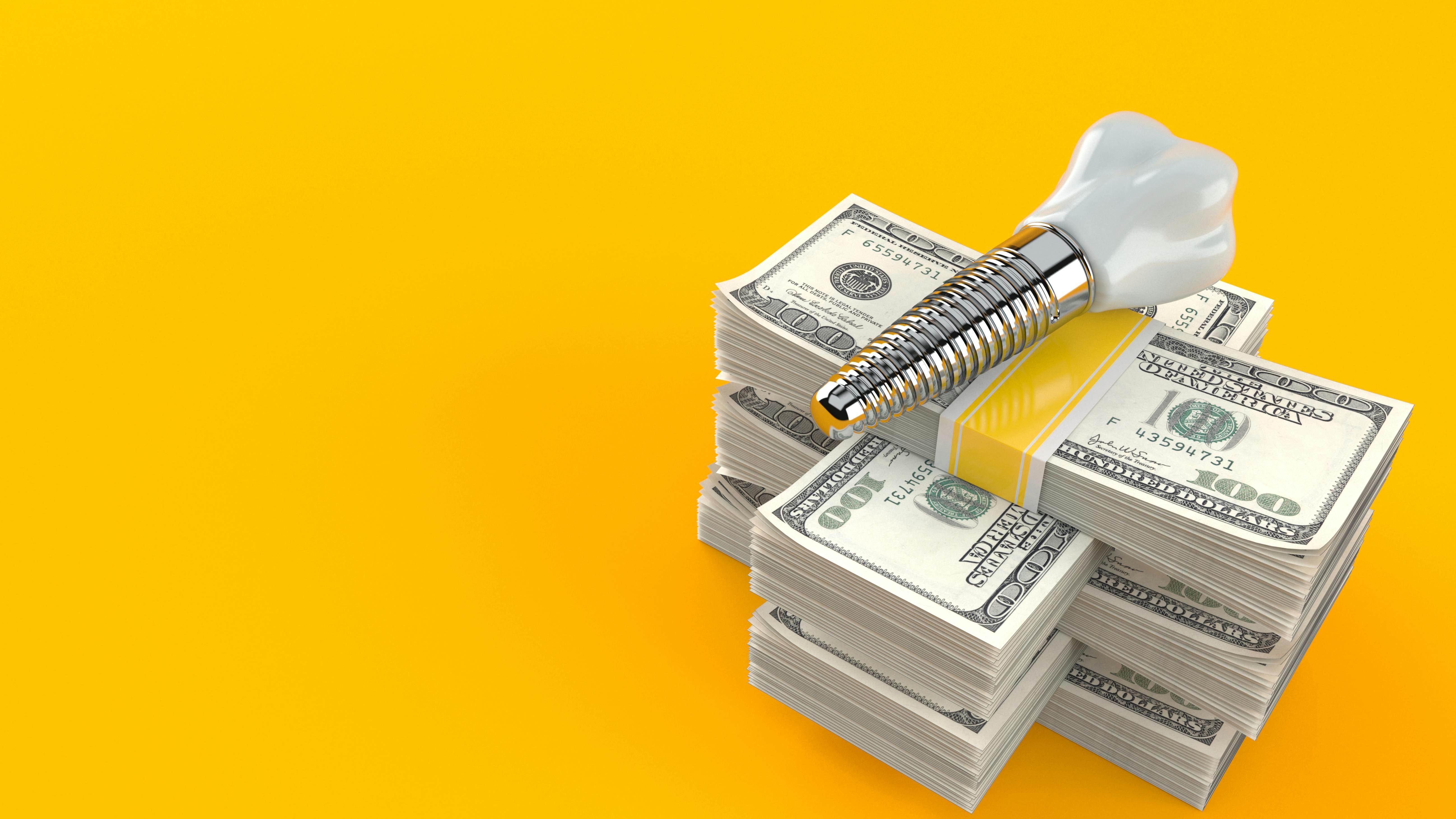 Stack of money with dental implant on top