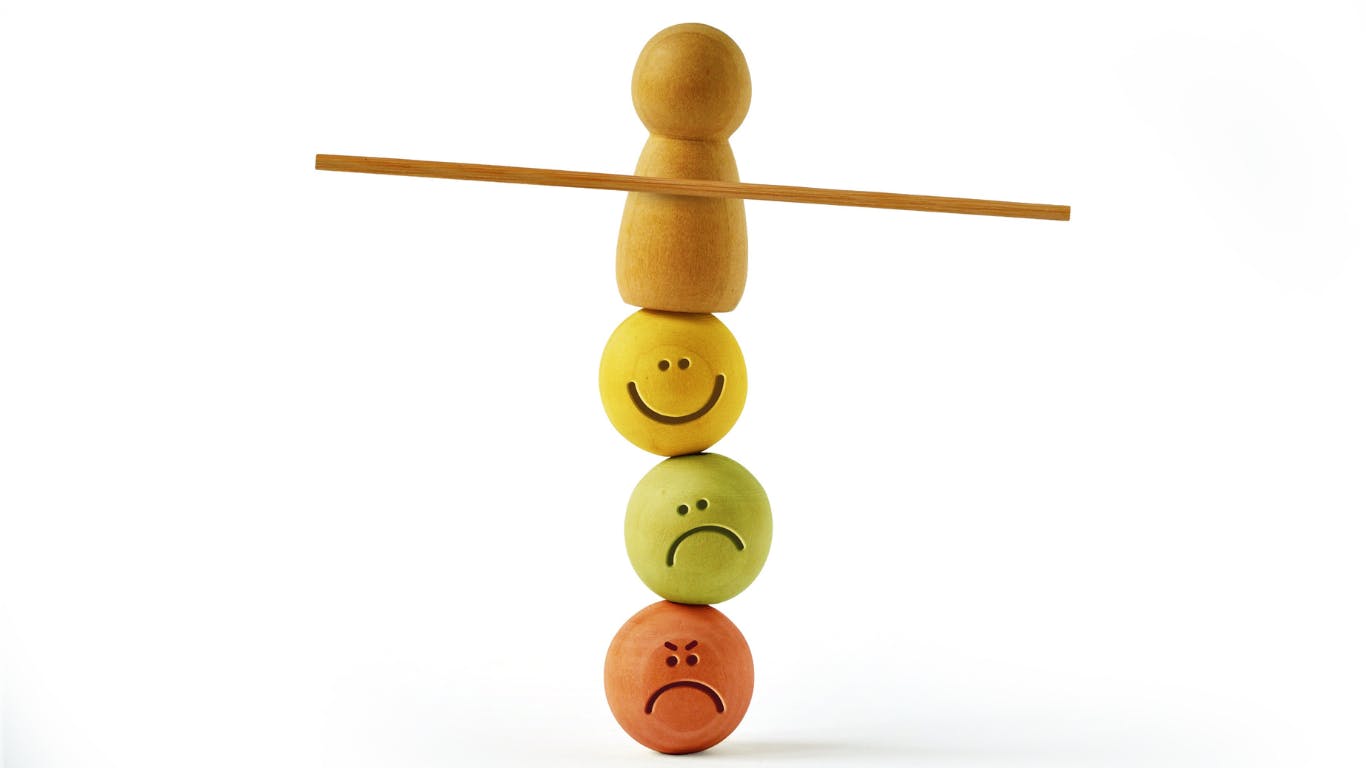 smiley faces and frowny faces balanced on top of each other